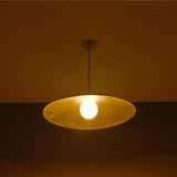 Aurelia Globe Saucer Pendant Light glowing in a dark setting with soft warm ambient lighting effect.