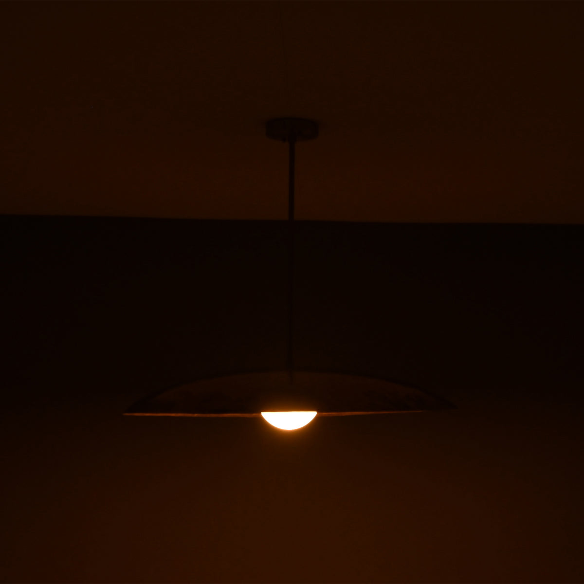 Side angle of Aurelia Petite Saucer Pendant Light highlighting the shallow dome profile and warm bulb glow.