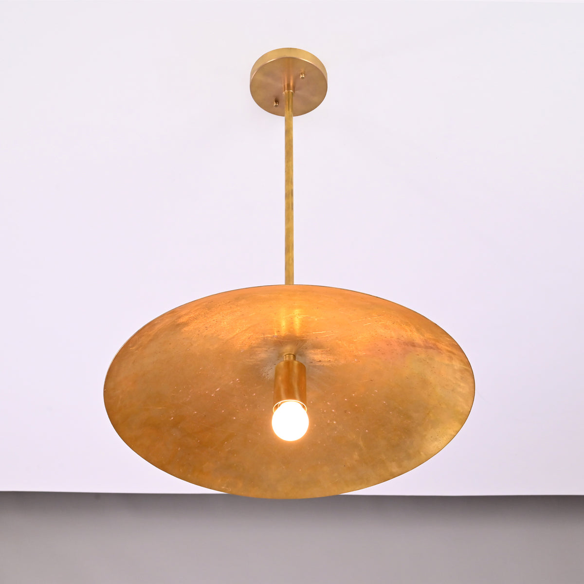 Underside view of Aurelia Petite Saucer Pendant Light showing the wide saucer shade and exposed glowing bulb.