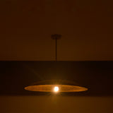 Wide saucer pendant light displayed in low light with warm exposed bulb and dramatic glow.