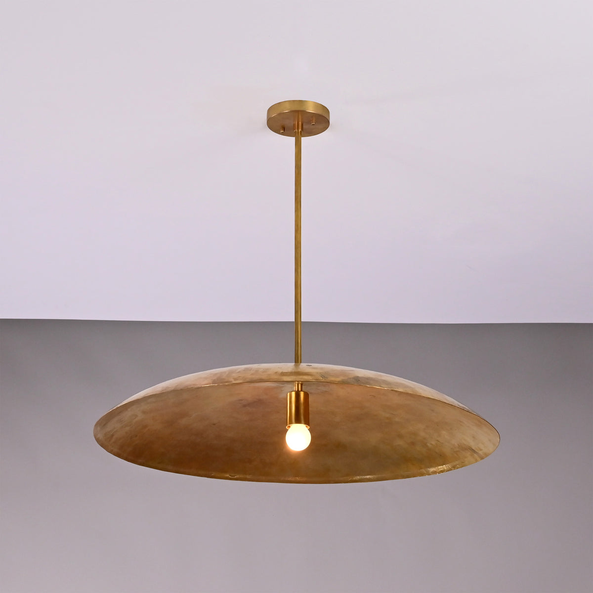 Aurelia Saucer Pendant Light with wide dome shade and single glowing bulb in front view.