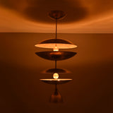 Aurelia Tiered Disc Chandelier glowing warmly with stacked sculptural discs and dramatic vertical ceiling light design.