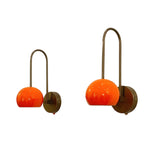 Two modern wall sconces with curved dark metal arms and vibrant orange glass shades, shown against a plain white background.