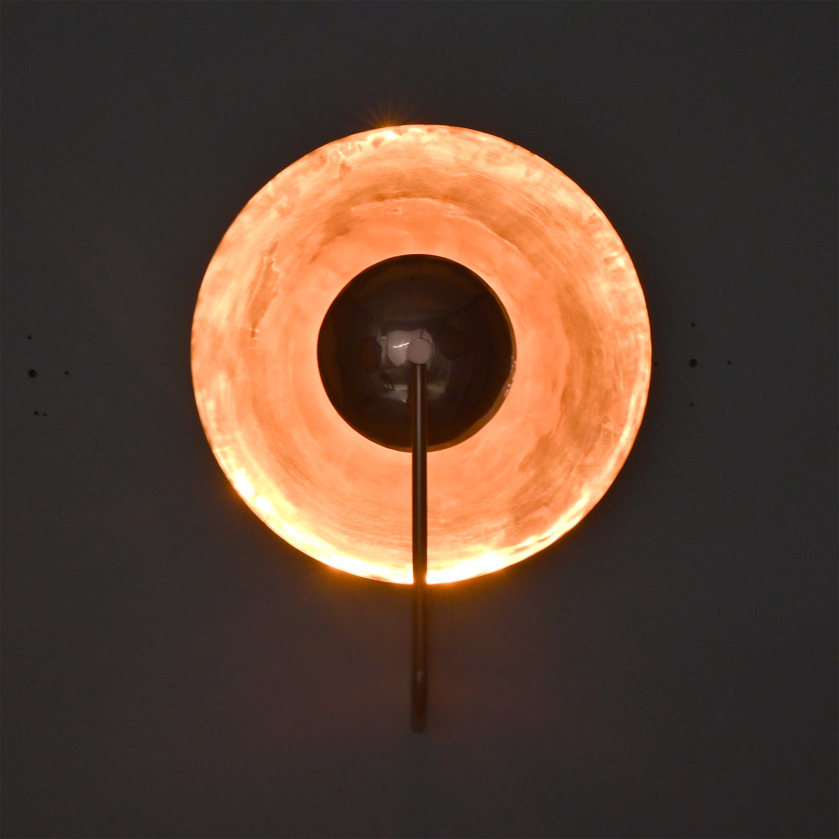Illuminated front view of the Aurora modern copper halo wall sconce casting a warm indirect glow through its polished circular reflector.
