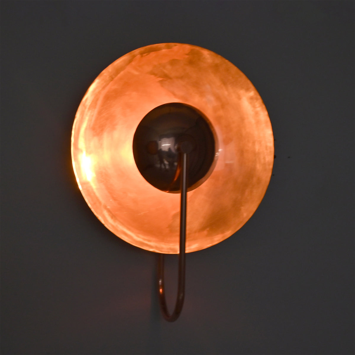 Warm glow view of the Aurora modern copper halo wall sconce highlighting its soft ambient illumination and sculptural halo-inspired design.