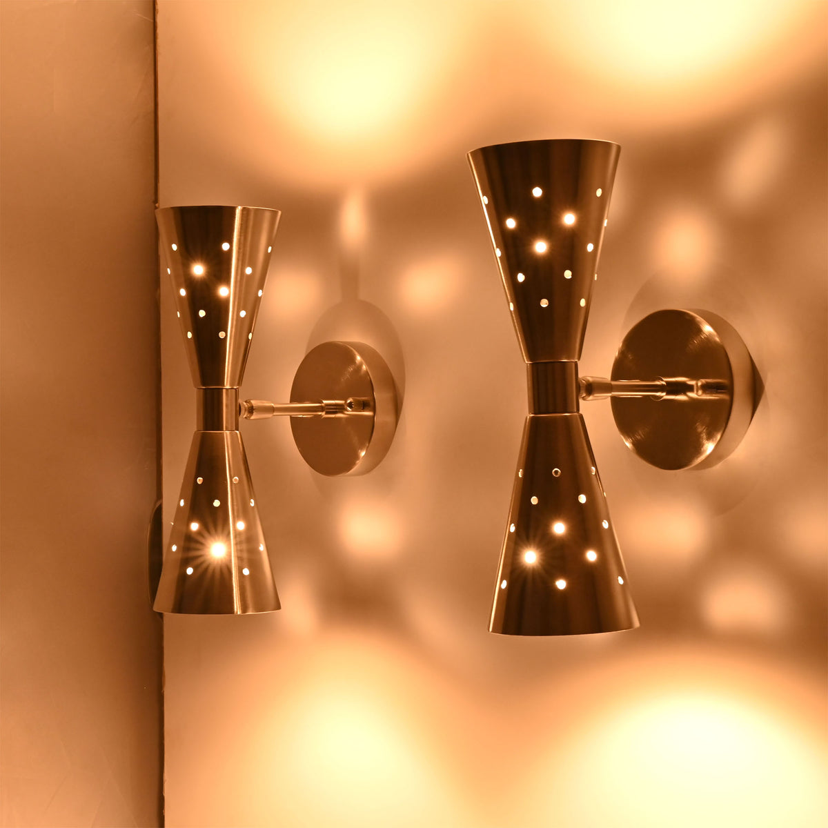 Side view of the Aurora perforated double cone wall sconce highlighting its sculptural hourglass silhouette and decorative lighting effects.