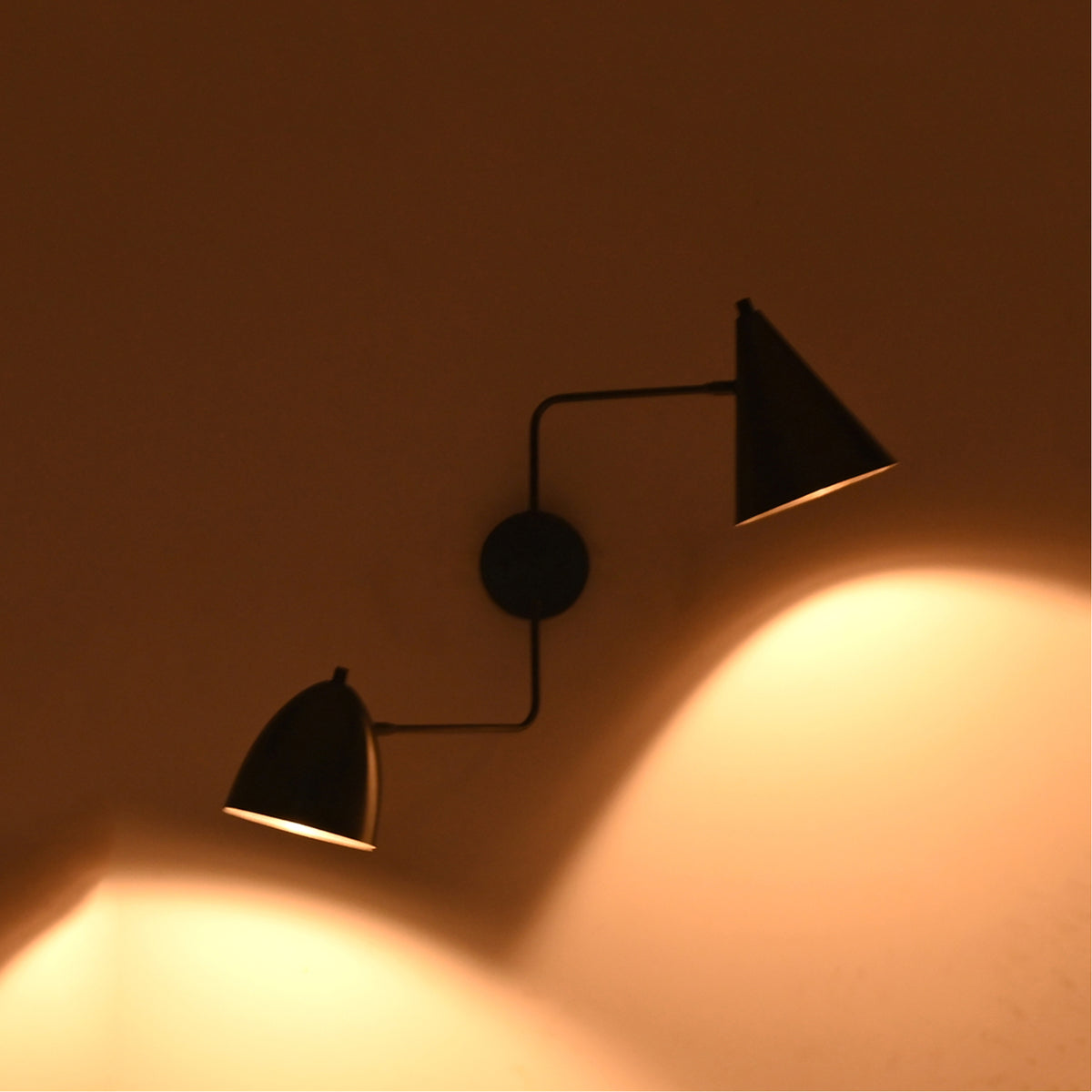 Ambient lighting view of the Aurora modern dual shade wall sconce creating balanced upward and downward illumination with dual matte black tapered metal shades.