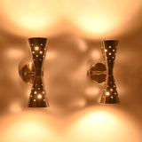 Aurora Modern Perforated Double Cone Wall Sconce illuminated with decorative perforated metal shades casting warm ambient light upward and downward.