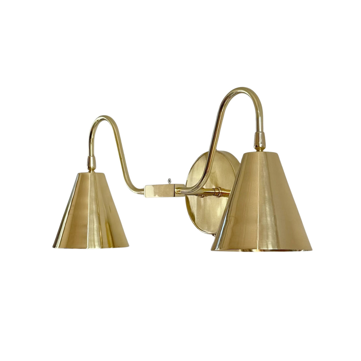 Angled view of the Aurora modern polished nickel double wall sconce showcasing dual tapered cone shades, curved metal arms, and a round wall backplate.