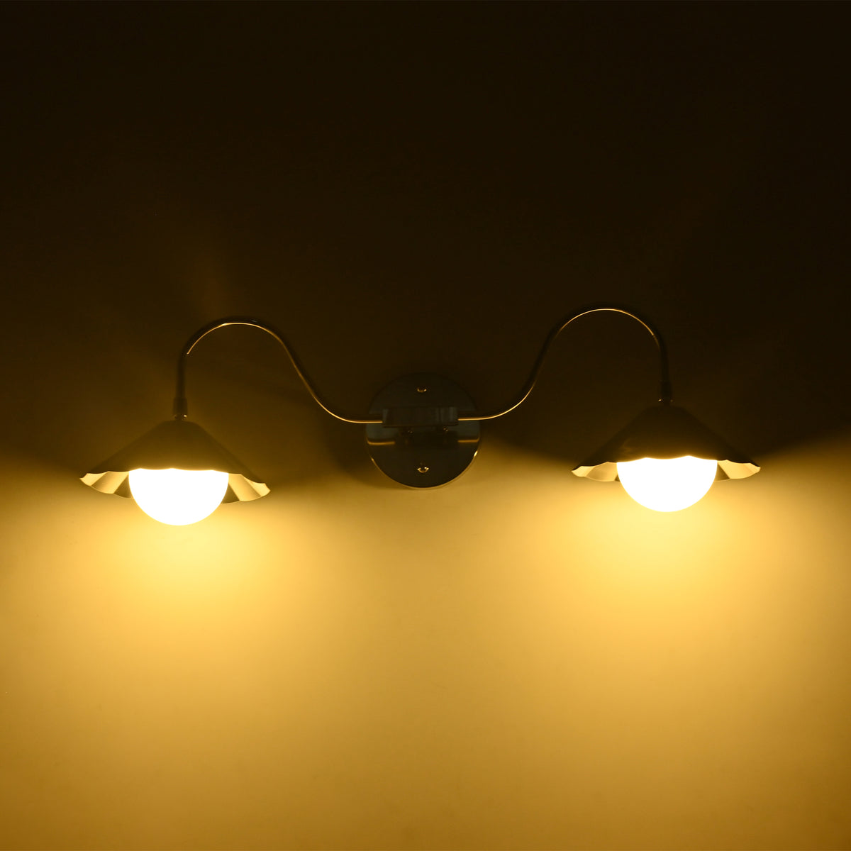 Illuminated Aurora modern polished nickel double wall sconce mounted on a wall, showcasing warm ambient lighting from dual frosted globe diffusers beneath fluted shades.
