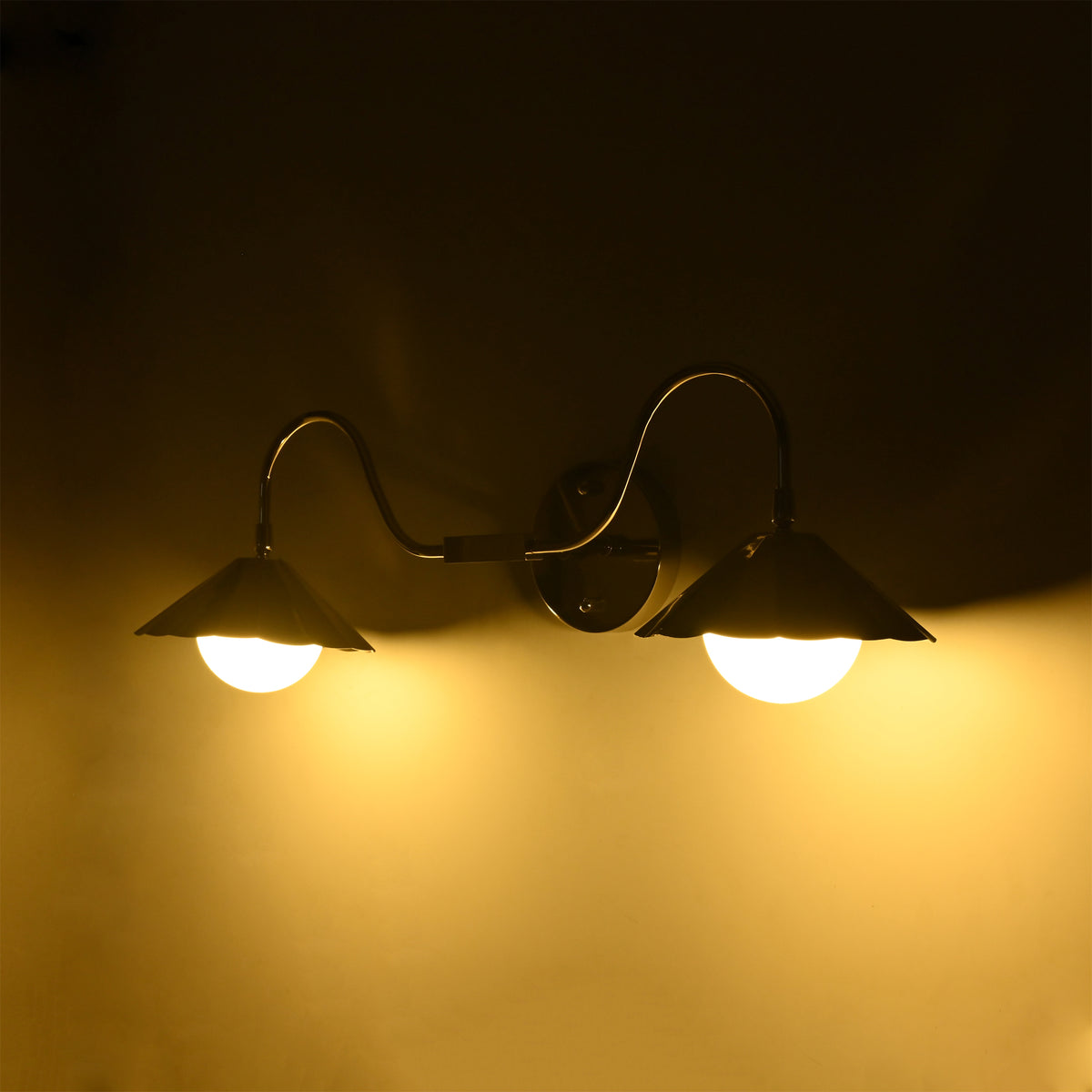 Perspective view of the Aurora modern polished nickel double wall sconce with illuminated frosted globe diffusers creating soft, even ambient lighting.