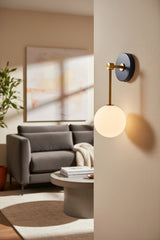 Aurora opal white glass globe wall sconce with brass stem and dark circular canopy, front product view