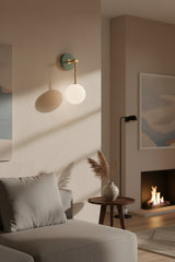 Aurora opal glass globe wall sconce with brass stem and green circular wall canopy