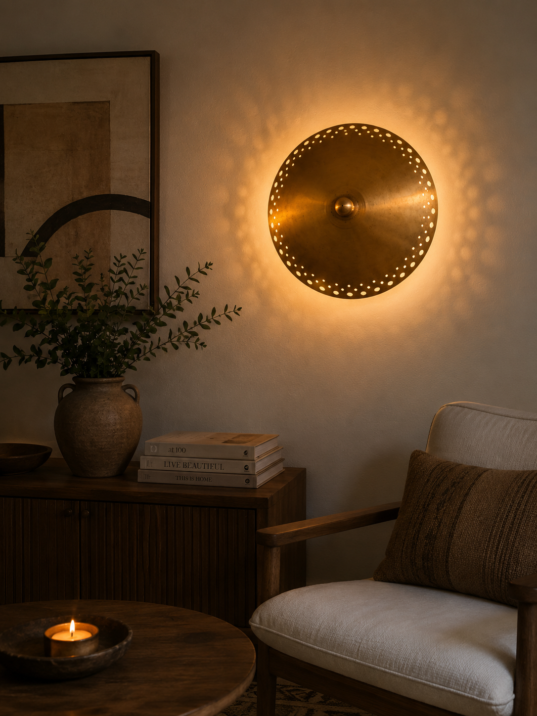 Aurora 3 light perforated brass bowl wall sconce illuminated in a warm modern living room interior