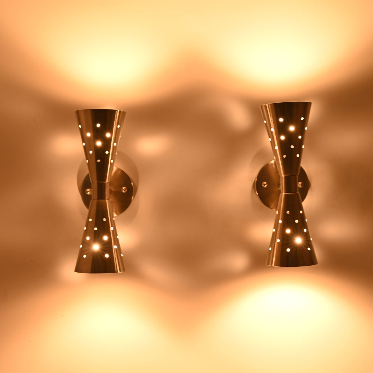 Pair of Aurora perforated double cone wall sconces creating decorative light patterns with warm ambient illumination.