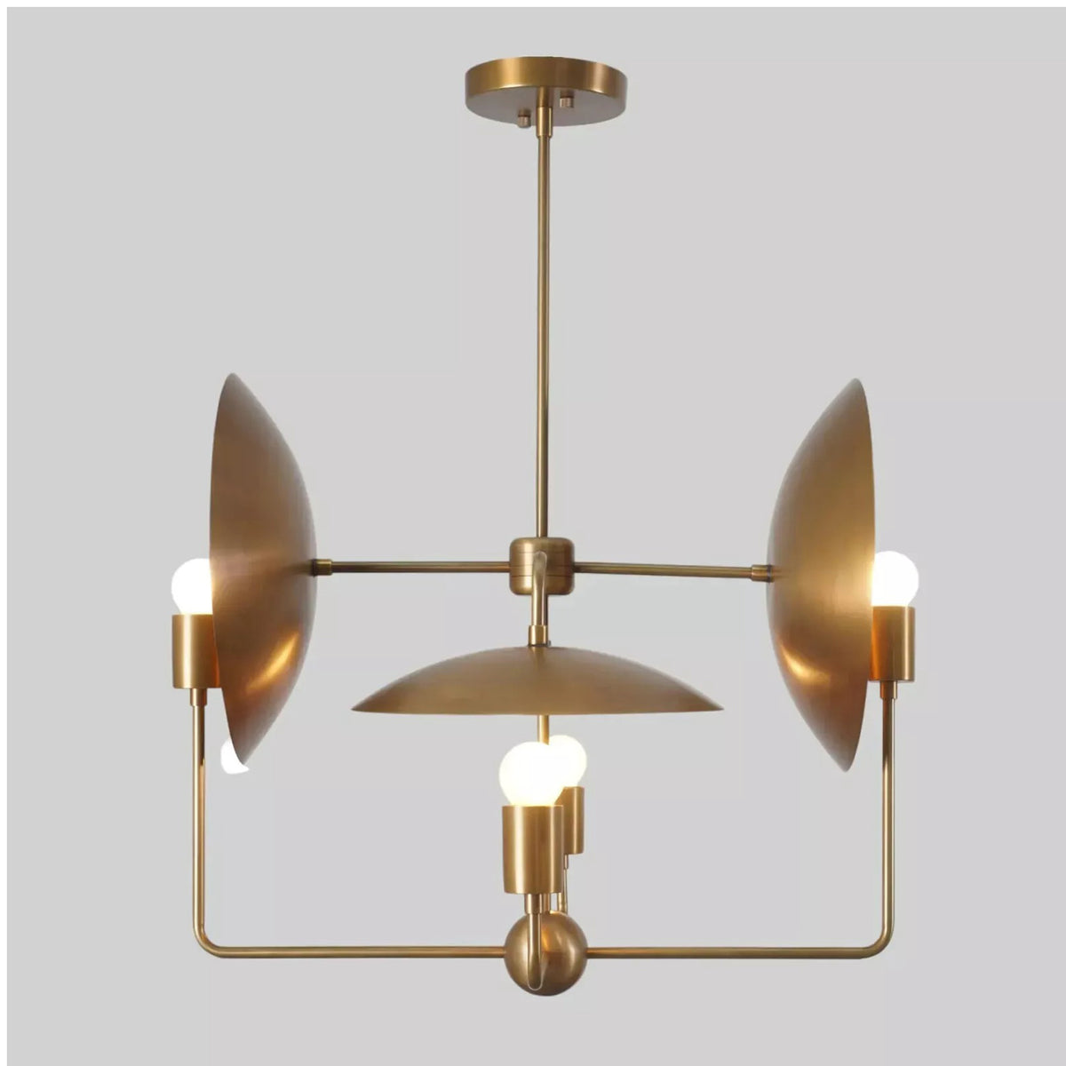 Front view of the Aurora Sculptural Disc Chandelier with four exposed globe bulbs, sculptural disc reflectors, central dome shade, and solid brass construction.