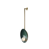 Angled view of Aurora modern wall sconce featuring deep green circular disc, frosted globe and brass frame – Model 32776