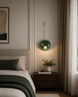 Aurora green disc wall sconce with globe light installed beside bed in a modern bedroom – Model 32776