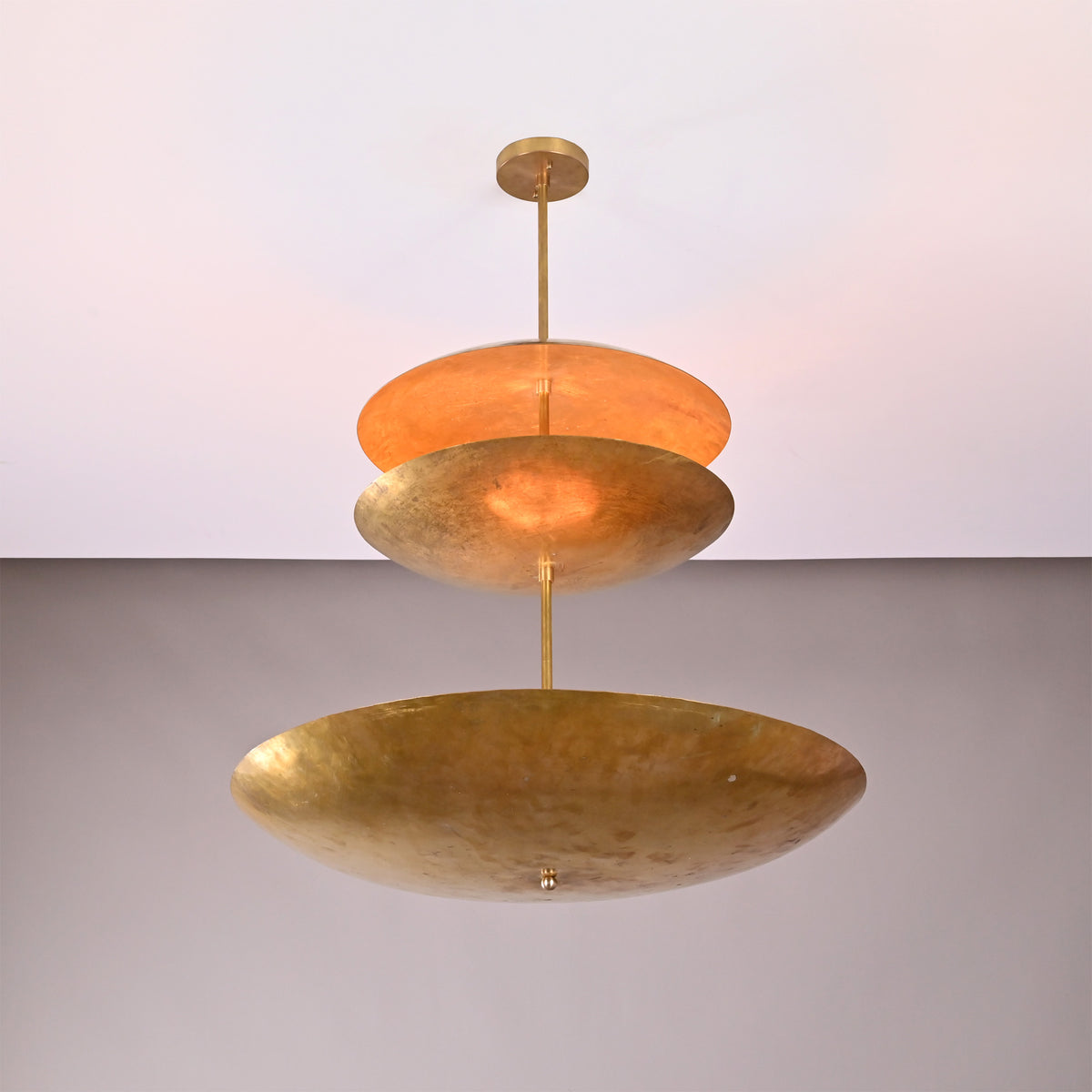 Close up of Aurora Triple Saucer Chandelier highlighting layered saucer shades and warm diffused illumination.