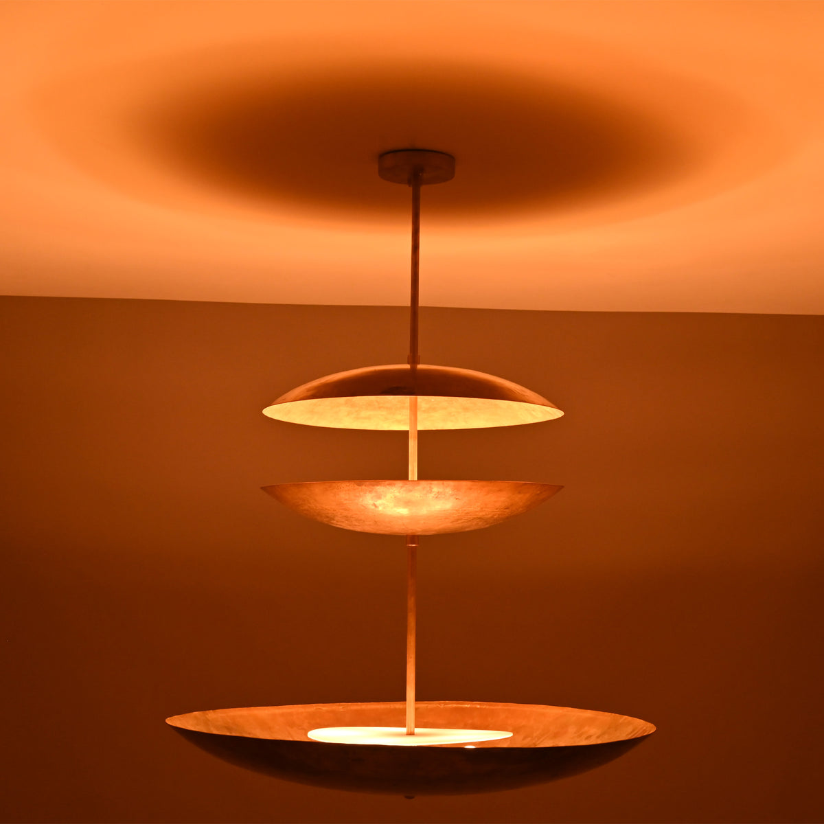 Side view of Aurora Triple Saucer Chandelier showing stacked circular shades and soft warm light effect.