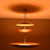 Side view of Aurora Triple Saucer Chandelier showing stacked circular shades and soft warm light effect.