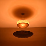 Aurora Triple Saucer Chandelier glowing warmly in low light with dramatic ambient ceiling illumination.
