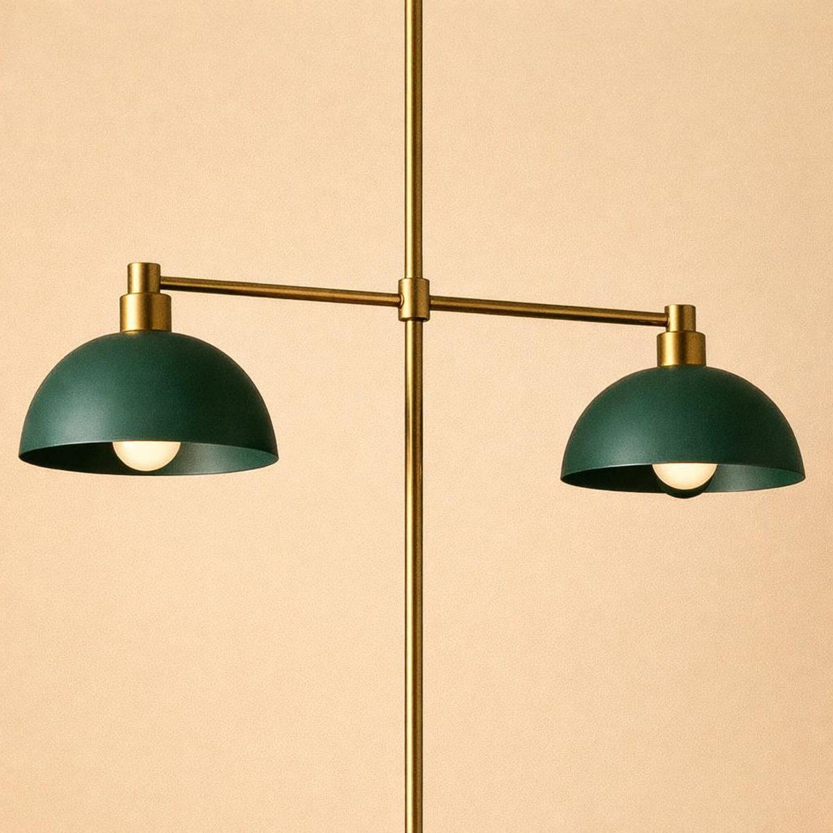 Symmetrical brass pendant light featuring two green dome shades mounted on a horizontal arm.