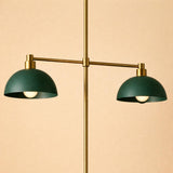 Symmetrical brass pendant light featuring two green dome shades mounted on a horizontal arm.