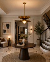 Belgravia brass double-disc pendant illuminating an elegant contemporary foyer with a round wood table and staircase.
