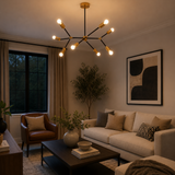 Berlin 8 light black and brass linear arm chandelier illuminated in a modern living room with warm ambient lighting.
