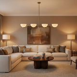 Bern 4 light linear chandelier shown from the front with ivory metal bowl shades and a slim brass frame.