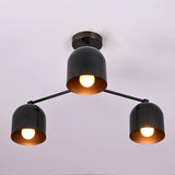 Minimalist black brass chandelier with three dome shades, glowing with warm light against a soft background.