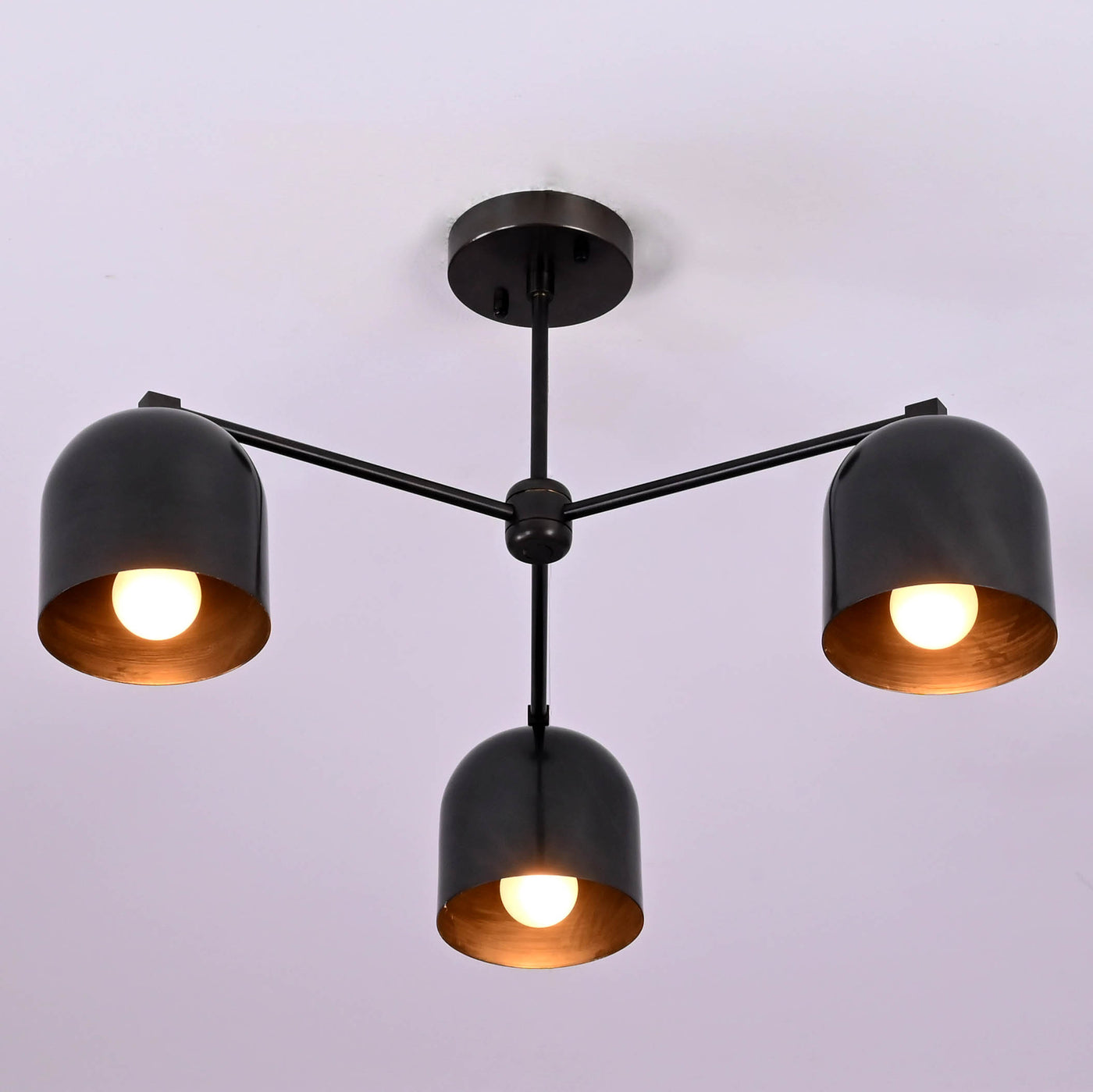 Modern 3-light black brass ceiling chandelier with dome-shaped shades, photographed in daylight against a white ceiling.