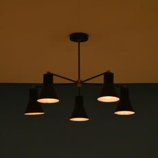 Elegant black brass chandelier with five cone shades, softly lit in a dark room, giving a warm and intimate atmosphere.