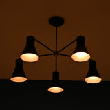 Modern black cone-shaped chandelier illuminated in a dark room, emitting a warm and inviting glow.