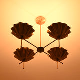 Brass bloom chandelier casting a radiant golden glow on the ceiling in a darkened room.