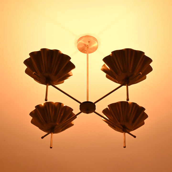 Brass bloom chandelier casting a radiant golden glow on the ceiling in a darkened room.