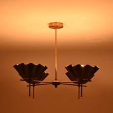 Brass bloom chandelier glowing warmly in a dim room, casting soft ambient lighting on the ceiling.