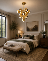 Bordeaux 13 light sculptural brass chandelier displayed above a refined contemporary bedroom with warm neutral decor.