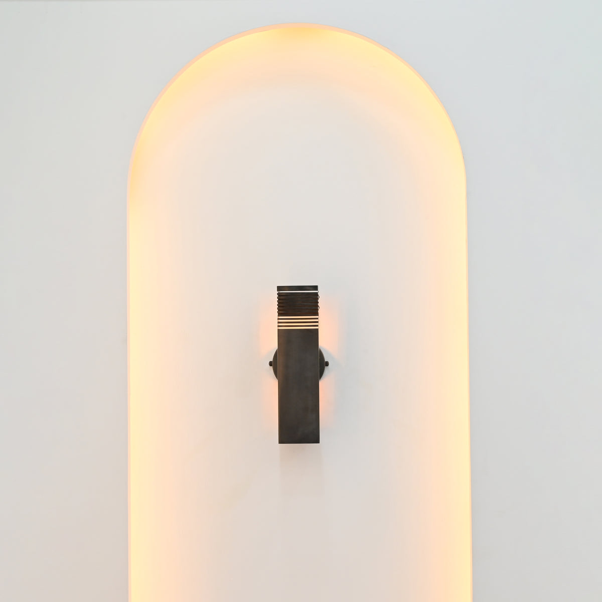 Boston 2-light vertical wall sconce installed in a minimalist white arched wall niche with subtle warm illumination and contemporary architectural styling.