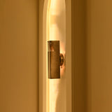 Side view of Boston 2-light linear wall sconce with warm golden illumination, dark metal construction, and horizontal slatted design inside an architectural wall niche.