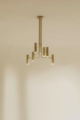Modern brass chandelier installed on ceiling, casting warm ambient light with clean architectural lines.
