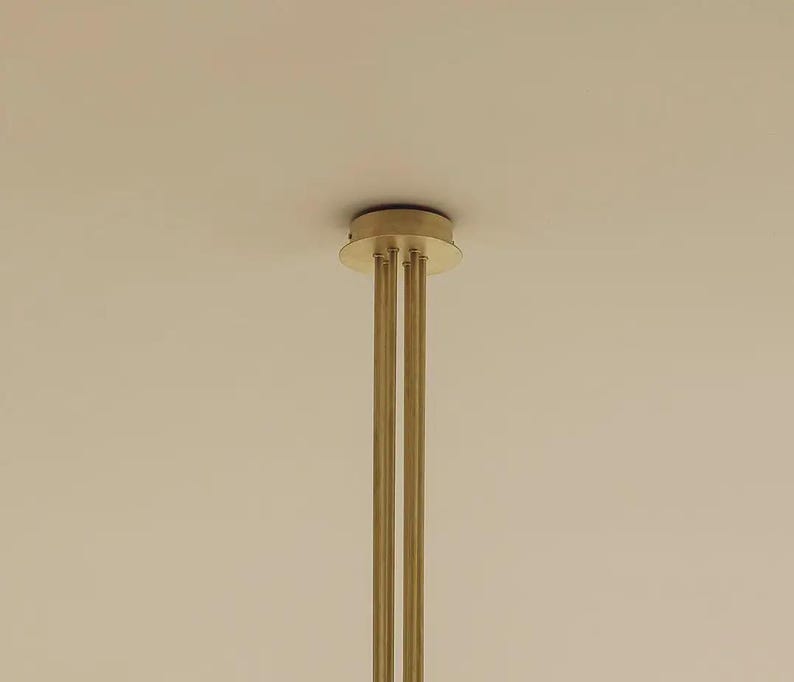 Close-up of brass ceiling canopy and downrod with smooth brushed finish and solid construction.