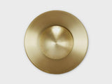 Top-down view of handcrafted brass disc flushmount ceiling light with circular sculpted form.