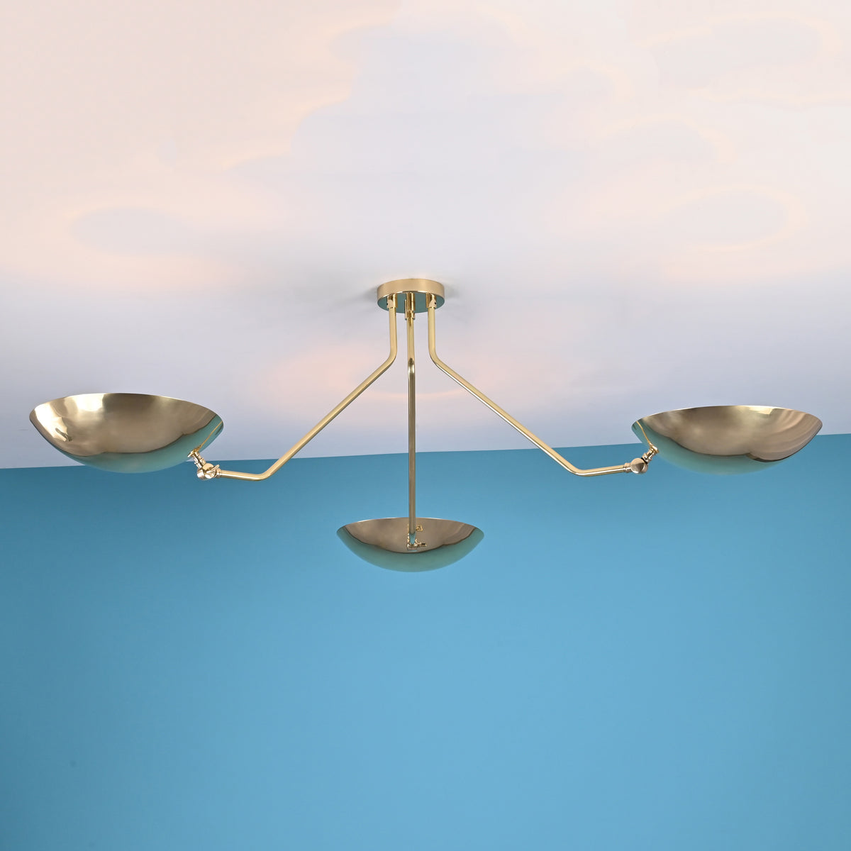 Side view of a brushed brass flushmount chandelier with three bowl-shaped shades and minimalist arms.