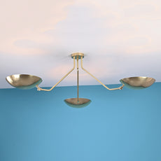 Side view of a brushed brass flushmount chandelier with three bowl-shaped shades and minimalist arms.