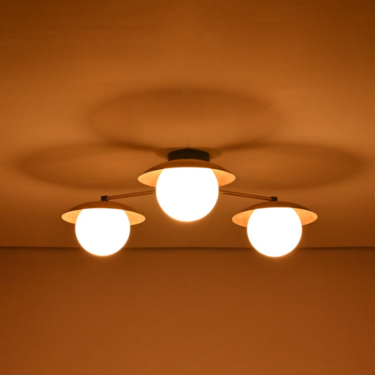 Brass chandelier with three frosted globe shades glowing warmly in the dark, providing cozy ambient light for bedrooms and living areas.