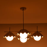 Handmade brass chandelier with three ruffled shades glowing warmly in the dark, offering ambient lighting and sculptural design.