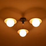 Brass chandelier with three frosted globes and disc shades glowing warmly at night, creating ambient lighting for cozy living spaces.