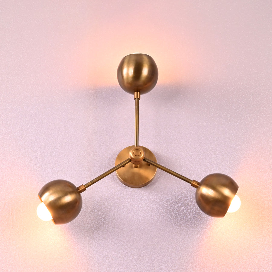 Modern brass flush mount ceiling light with three spherical shades in brushed brass finish, photographed against a light background.